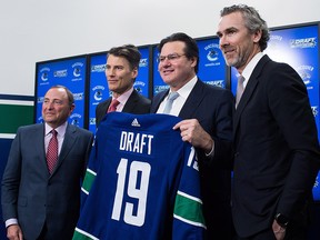 NHL commissioner Gary Bettman, from left to right, Vancouver mayor Gregor Robertson, Vancouver Canucks owner Francesco Aquilini and team president Trevor Linden pose for photographs with a jersey after announcing the 2019 NHL Draft will be held in Vancouver, during a news conference on Wednesday, February 28, 2018. (THE CANADIAN PRESS/Darryl Dyck)