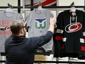 Kurt Cusac, a worker at The Eye store, straightens out Hartford Whalers T-shirts at PNC Arena in Raleigh, N.C., Feb. 1, 2018. (Chris Seward/The News & Observer via AP)