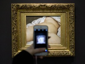 In this Feb.12 2016 file photo, a visitor takes a picture of Gustave Courbet's 1866 "The Origin of the World," at Musee d'Orsay museum, in Paris. A French teacher, whose Facebook account was suspended in 2011 after he posted a photo of a famous 19th-century nude painting, is suing Thursday Feb. 1, 2018 the California-based social network Facebook for alleged "censorship". Frederic Durand-Baissas, a 59-year-old Parisian teacher and art lover, posted a photo of "The Origin of the World," which depicts female genitalia.