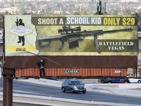 Workers remove a billboard poster for the Battlefield Vegas shooting range after it was vandalized on March 1, 2018 in Las Vegas, Nevada.