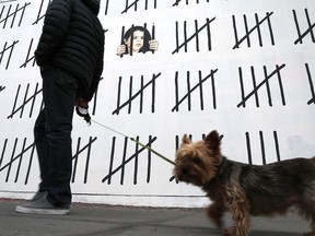 Pedestrians walk by the latest work by the elusive British street artist Bansky along a wall on Houston street in Manhattan on March 16, 2018 in New York City.