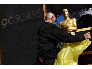 A worker takes away the plastic cover of a statue on the red carpet a few hours before the "Oscars", the 90th Annual Academy Awards on March 4, 2018, in Hollywood, California.