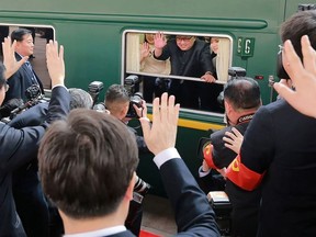 This picture from North Korea's official Korean Central News Agency (KCNA) taken on March 27, 2018 and released on March 28, 2018 shows North Korean leader Kim Jong Un (C) waving from his train as it prepares to depart from Beijing railway station.
