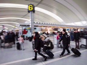 Air Canada has confirmed a system outage is leading to service interruptions as angry passengers take to Twitter to complain about long lines and flight delays. People carry luggage at Pearson International Airport in Toronto on December 20, 2013.
