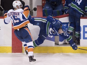 New York Islanders winger Cal Clutterbuck (15) checks Vancouver Canucks winger Brock Boeser (6) in Vancouver, Monday, March 5, 2018. (THE CANADIAN PRESS/Jonathan Hayward)