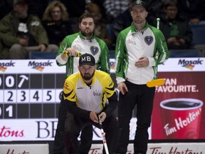 Manitoba skip Reid Carruthers of Winnipeg looks down the ice as Saskatchewan skip Steve Laycock, (R) fourth Matt Dunstone, stand in the back of the house during their draw 3 game at the Tim Hortons Brier, March 4, 2018. (Michael Burns/Postmedia Network)