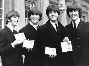 In this Oct. 26, 1965 file photo The Beatles, from left: Ringo Starr, John Lennon, Paul McCartney and George Harrison smile as they display the Member of The Order of The British Empire medals presented to them by Queen Elizabeth II in a ceremony in Buckingham Palace in London, England.