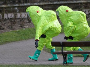 Personnel in hazmat suits walk away after securing the covering on a bench in the Maltings shopping centre in Salisbury, England on Thursday March 8, 2018, where former Russian double agent Sergei Skripal and his daughter Yulia were found critically ill by exposure to a nerve agent.