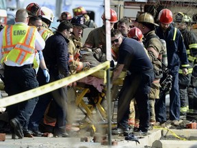 Emergency personnel move an injured firefighter to an ambulance after a wall collapse at the scene of a fire in York, Pa., Thursday, March 22, 2018.