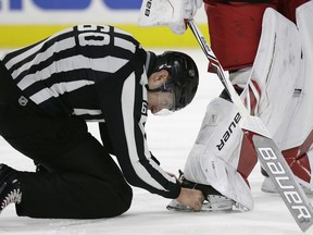 An official removes the puck lodged in Carolina Hurricanes goalie Cam Ward's skate during a game against the Arizona Coyotes in Raleigh, N.C., Thursday, March 22, 2018.