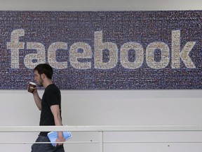 In this March 15, 2013, file photo, a Facebook employee walks past a sign at Facebook headquarters in Menlo Park, Calif.