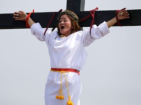 Maryjane Sazon, a 39-year-old beauty salon worker, grimaces as she gets nailed to the cross as part of Good Friday rituals in the village of San Pedro Cutud, Pampanga province, northern Philippines Friday, March 30, 2018.  (AP Photo/Aaron Favila)