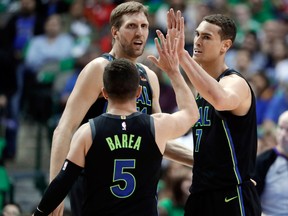 Dallas Mavericks J.J. Barea, Dwight Powell and Dirk Nowitzki celebrate a basket during the first half of an NBA game against the Denver Nuggets in Dallas on March 6, 2018