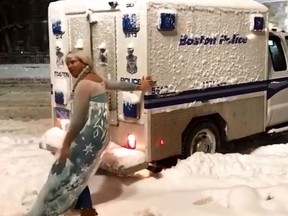 A man dressed as Queen Elsa from 'Frozen' helps push a Boston Police wagon that was stuck in snow. (YouTube/The Weather Network)