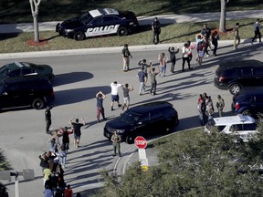 In this Feb. 14, 2018 file photo, students hold their hands in the air as they are evacuated by police from Marjory Stoneman Douglas High School in Parkland, Fla., after a shooter opened fire on the campus. (Mike Stocker/South Florida Sun-Sentinel via AP)