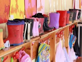 This stock photo shows boots and backpacks on the wall of a kindergarten classroom.