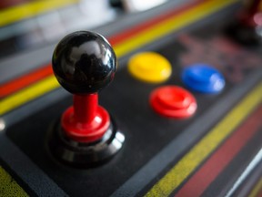 This stock photo shows a closeup of a joystick on a vintage arcade machine.
