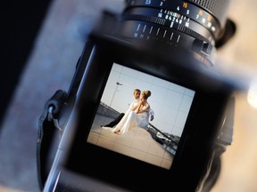 A wedding photographer takes pictures of a bride and groom in this stock photo.