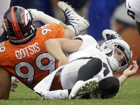 In this photo taken Oct. 1, 2017, Oakland Raiders quarterback Derek Carr, right, grabs his back after being sacked by Denver Broncos defensive ends Adam Gotsis in Denver.  (AP Photo/Jack Dempsey)