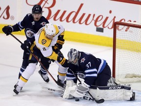 Winnipeg Jets' Dmitry Kulikov (5) tries to stop Nashville Predators' Kyle Turris (8) as he gets a shot on goaltender Connor Hellebuyck (37) during first period NHL hockey action in Winnipeg, Tuesday, February 27, 2018. THE CANADIAN PRESS/Trevor Hagan ORG XMIT: WPGT104