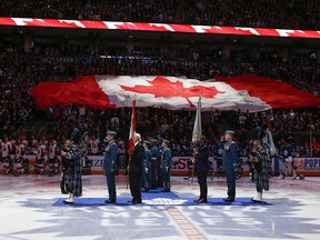 Former Toronto Maple Leafs Darryl Sittler (left) and Darcy Tucker (right) receive the flag and colours of the Canadian Armed Forces in Toronto on Saturday February 10, 2018. (Jack Boland/Toronto Sun)