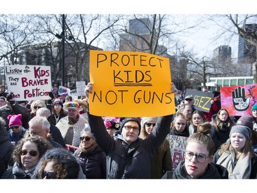 People hold up signs during a 'March for Our Lives' rally to show solidarity with the U.S. gun control movement in Montreal, Saturday, March 24, 2018.