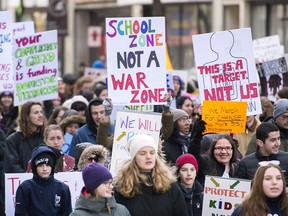 People hold up signs during a 'March of Our Lives' rally to show solidarity with the U.S. gun control movement in Montreal, Saturday, March 24, 2018. THE CANADIAN PRESS/Graham Hughes