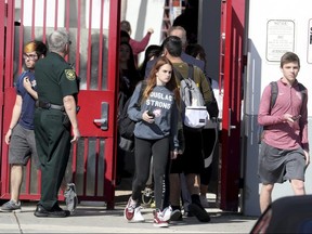 Marjory Stoneman Douglas High School students walk out of the building on Wednesday, March 14, 2018 in Parkland, Fla.