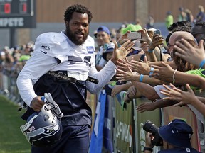 Seattle Seahawks' Michael Bennett greets fans as he heads to the practice field during training camp Friday, Aug. 4, 2017, in Renton, Wash. (AP Photo/Elaine Thompson)