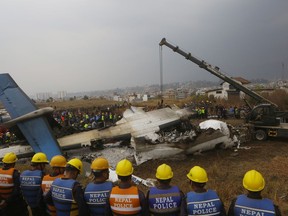 Nepalese rescuers and police are seen near the debris after a passenger plane from Bangladesh crashed at the airport in Kathmandu, Nepal, Monday, March 12, 2018. The passenger plane carrying 71 people from Bangladesh crashed and burst into flames as it landed Monday in Kathmandu, Nepal's capital, killing dozens of people, officials said.