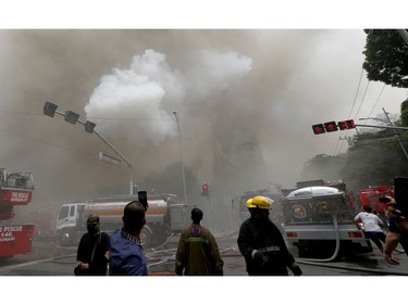 People, right, take cover as an explosion is heard during a fire that engulfs the Manila Pavilion Hotel and Casino Sunday, March 18, 2018 in Manila, Philippines. (AP Photo/Bullit Marquez)