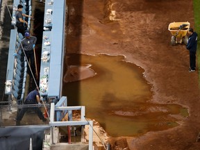 Workers sweep the water away after a water pipe broke near third base at Dodger Stadium, after an exhibition baseball game between the Los Angeles Dodgers and the Los Angeles Angels on March 27, 2018
