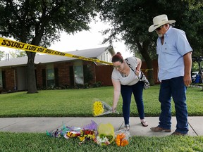 Kelsey Moss, who knew three of the victims, places flowers at a makeshift memorial site with her father Hal Moss of Plano, Texas, before saying a prayer for the eight victims in a shooting on West Spring Creek Parkway in Plano on Tuesday, Sept. 12, 2017.   (Vernon Bryant/The Dallas Morning News via AP)