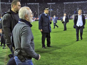 PAOK owner, businessman Ivan Savvidis, invades the pitch during a Greek League match between PAOK and AEK Athens in Thessaloniki, Sunday, March 11, 2018.  (InTime Sports via AP)