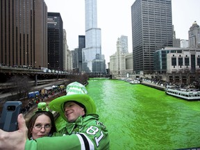 Stacey Peterson and Kevin McGuire take a selfie in front of the green Chicago River to celebrate St. Patrick's Day, Saturday, March 17, 2018.  (James Foster/Chicago Sun-Times via AP)