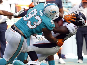 In this Dec. 3, 2017, file photo, Miami Dolphins defensive tackle Ndamukong Suh (93) tackles Denver Broncos running back C.J. Anderson (22) in Miami Gardens, Fla. (AP Photo/Wilfredo Lee, File)