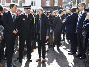 Britain's Prime Minister Theresa May, centre, is briefed by members of the police as she views the area where former Russian double agent Sergei Skripal and his daughter were found critically ill, in Salisbury, England, Thursday, March 15, 2018.  (Toby Melville/PA via AP)