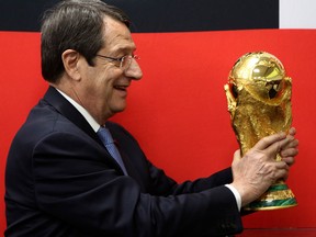 Cyprus' President Nicos Anastasiades holds the FIFA World Cup trophy during its world tour at a stop at international airport in southern city of Larnaca, Cyprus, on Feb. 16, 2018