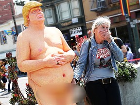 A passerby has a picture taken with a statue depicting republican presidential nominee Donald Trump in the nude on August 18, 2016 in San Francisco, United States. (Getty)