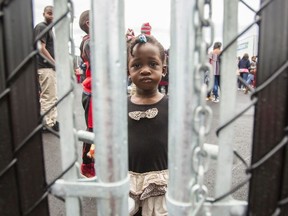 This file photo taken on August 5, 2017 shows a girl who crossed the Canada/US border illegally with her family, claiming refugee status in Canada,as she looks through a fence at a temporary detention centre in Blackpool, Quebec.