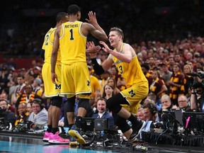 Moritz Wagner #13 of the Michigan Wolverines is helped back to the court by teammates after jumping over the scorer's table in the second half against the Loyola Ramblers during the 2018 NCAA Men's Final Four Semifinal at the Alamodome on March 31, 2018 in San Antonio, Texas.