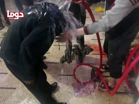 An image grab taken from a video released by the Douma City Coordination Committee shows unidentified volunteers spraying a man with water at a make-shift hospital following an alleged chemical attack on the rebel-held town of Douma on April 7, 2018.
