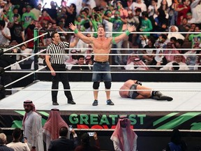 John Cena (C) celebrates defeating Triple H (R) during the World Wrestling Entertainment (WWE) Greatest Royal Rumble event in the Saudi coastal city of Jeddah on April 27, 2018.