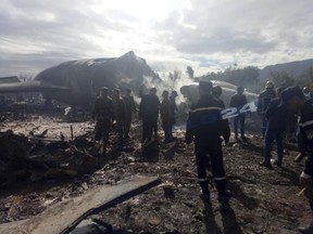 This image dated Wednesday, April 11, 2018, and posted by Algerian news agency ALG24, shows firefighters and soldiers at the scene of a fatal military plane crash near Boufarik military base near the Algerian capital, Algiers. (ALG24 via AP)