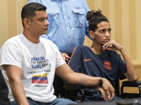 Anthony Borges, 15, right, who was shot multiple times on Feb. 14 in the Marjory Stoneman Douglas High School massacre, sits next to his father, Roger Borges, left, during a news conference, April 6, 2018, in Plantation, Fla. (Jennifer Lett/South Florida Sun-Sentinel via AP)