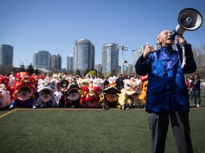 A man uses a bullhorn to organize a group photo of lion dancers and performers during a Chinatown Culture Day event coinciding with Vancouver Mayor Gregor Robertson delivering an apology on behalf of the city for past discrimination against residents of Chinese descent, during a special city council meeting in Chinatown, in Vancouver on Sunday April 22, 2018. (THE CANADIAN PRESS/Darryl Dyck)
