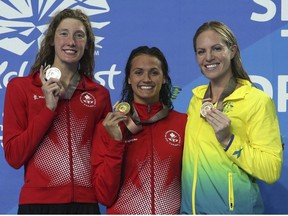 Women's 200m backstroke gold medalist Canada's Kylie Masse, centre, stands with silver medalist and compatriot Taylor Ruck, left, and bronze medalist Australia's Emilt Seebohm on the podium at the Aquatic Centre during the 2018 Commonwealth Games on the Gold Coast, Australia, Sunday, April 8, 2018.