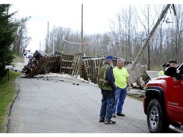 In this Monday, April 23, 2018 photo, people stand at the scene where a Case Farms chicken truck flipped after striking a utility pole in Washington Township, Ohio.