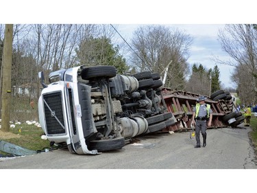 In this Monday, April 23, 2018 photo, a state trooper walks alongside an overturned semi tractor trailer that crashed in Washington Township, Ohio. Hundreds of chickens in containers were either killed or injured in the crash. The driver was not injured.