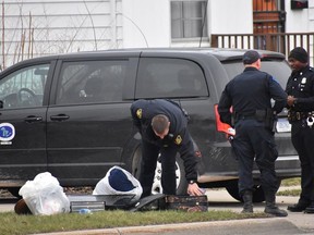 In this Wednesday, April 18, 2018 photo, officers investigate after two infant children were allegedly left in a suitcase along West Pierson Pierson Road in Flint, Mich.